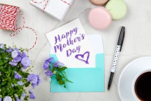 Creative Mother's Day card setup with flowers, coffee, and macarons on a marble table.